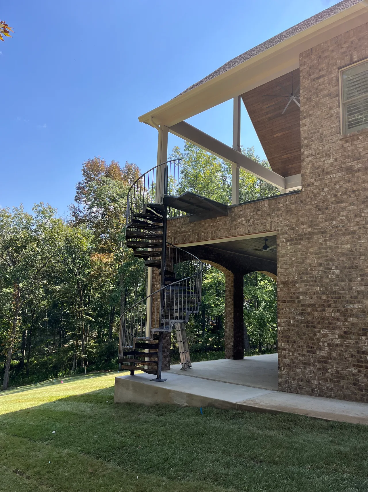 Exterior metal spiral staircase connecting a patio to an upper balcony